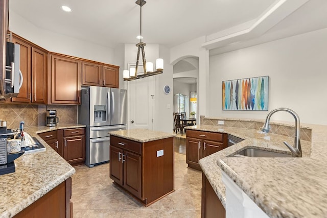 114 Fred Couples Dr, Round Rock, TX 78664 - kitchen with stainless steel appliances, a sink, arched walkways, light stone counters, and backsplash