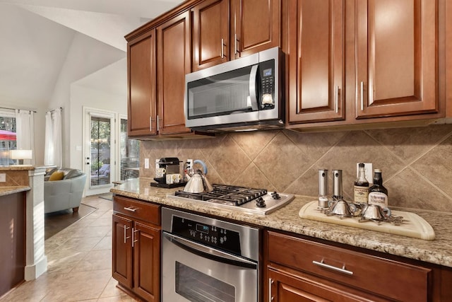 114 Fred Couples Dr, Round Rock, TX 78664 - kitchen with appliances with stainless steel finishes, backsplash, vaulted ceiling, light stone counters, and light tile patterned flooring