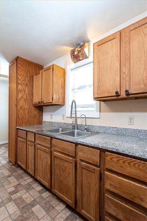 461 Skyline Rdg, San Marcos, TX 78666 - kitchen with a sink, brown cabinets, and brick patterned floors