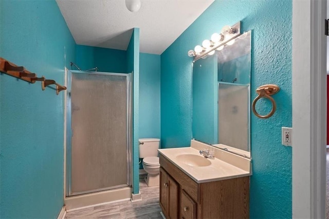 461 Skyline Rdg, San Marcos, TX 78666 - full bathroom with a textured wall, toilet, a shower stall, vanity, and wood finished floors