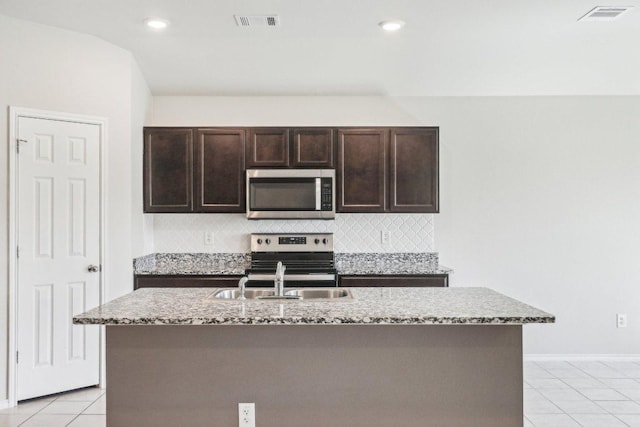 9701 Kensley Rose Dr, Killeen, TX 76542 - kitchen with stainless steel appliances, a sink, dark brown cabinetry, light tile patterned floors, and tasteful backsplash