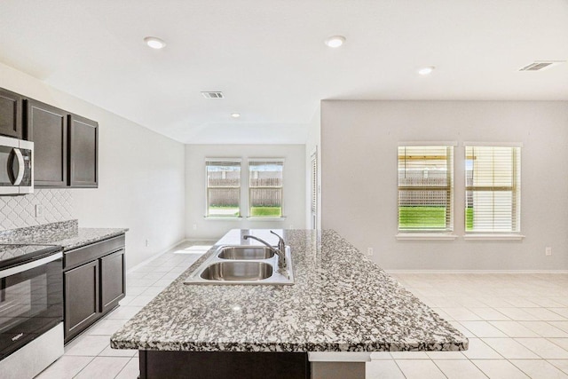 9701 Kensley Rose Dr, Killeen, TX 76542 - kitchen with appliances with stainless steel finishes, a sink, light tile patterned floors, tasteful backsplash, and a center island with sink