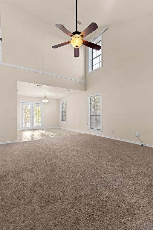 10 Saul St, Lampasas, TX 76550 - unfurnished living room featuring a high ceiling, plenty of natural light, carpet, baseboards, and a ceiling fan