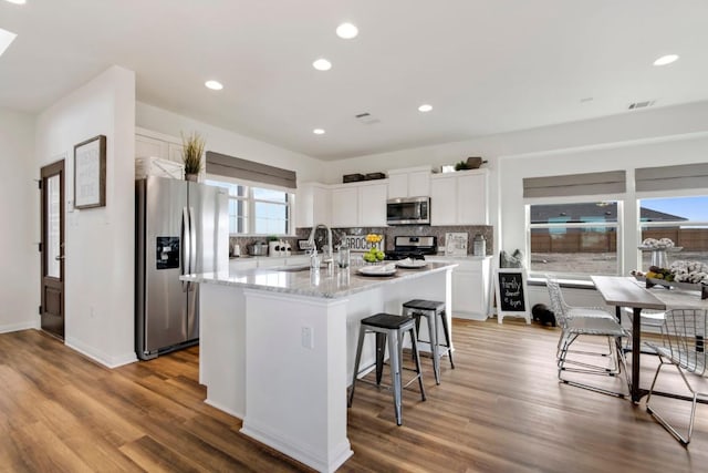 8169 Daisy Cutter Xing, Georgetown, TX 78626 - kitchen featuring appliances with stainless steel finishes, a sink, backsplash, light wood-style flooring, and an island with sink