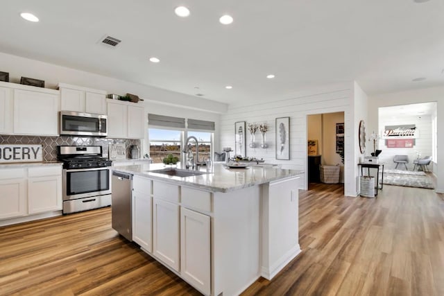 8169 Daisy Cutter Xing, Georgetown, TX 78626 - kitchen with stainless steel appliances, a sink, white cabinets, light wood-style floors, and recessed lighting