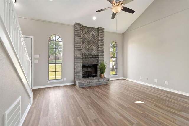 1145 Lago Vista St, San Marcos, TX 78666 - unfurnished living room featuring stairway, a ceiling fan, wood finished floors, a fireplace, and high vaulted ceiling