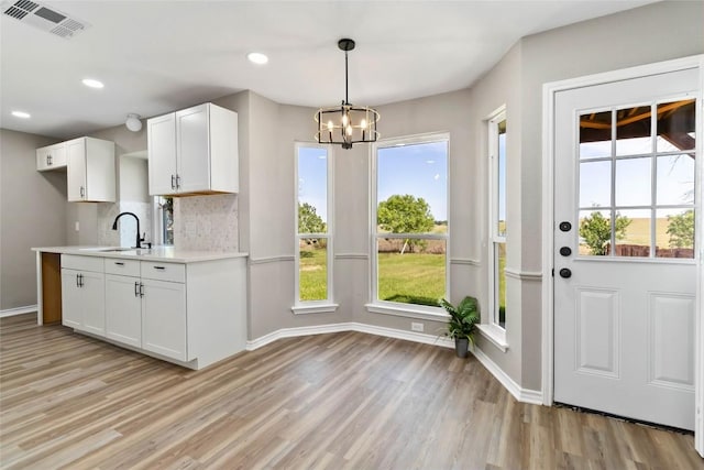 1145 Lago Vista St, San Marcos, TX 78666 - kitchen with a sink, light wood-type flooring, light countertops, a chandelier, and white cabinets