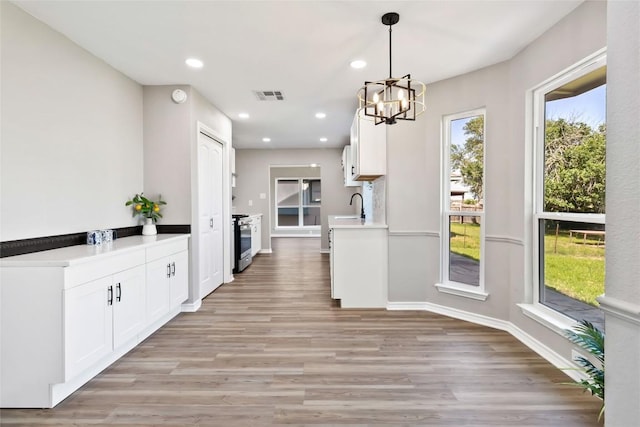 1145 Lago Vista St, San Marcos, TX 78666 - kitchen with stainless steel range with gas cooktop, light wood finished floors, a chandelier, light countertops, and recessed lighting