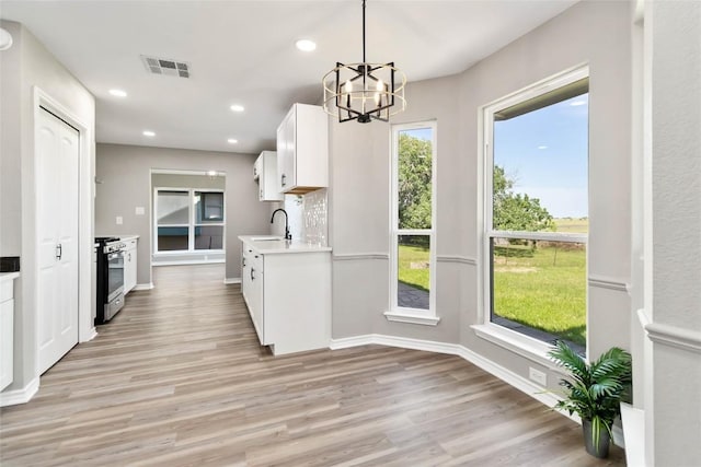 1145 Lago Vista St, San Marcos, TX 78666 - kitchen featuring a sink, stainless steel gas stove, light wood-style floors, white cabinetry, and light countertops