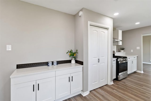 1145 Lago Vista St, San Marcos, TX 78666 - kitchen with stainless steel gas range, light wood finished floors, white cabinetry, light countertops, and recessed lighting