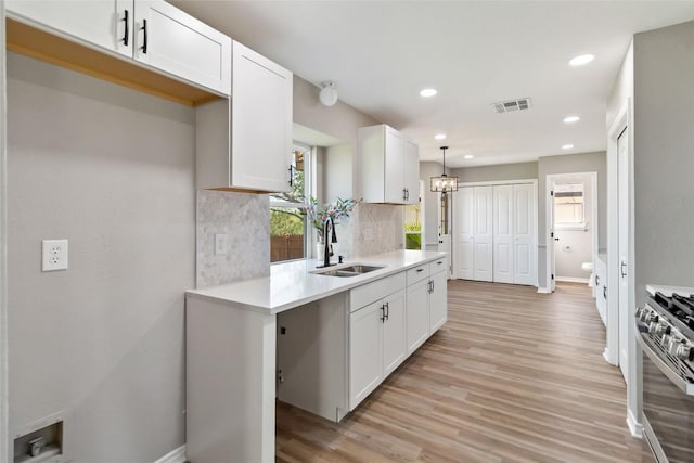 1145 Lago Vista St, San Marcos, TX 78666 - kitchen featuring a sink, stainless steel gas range oven, light wood-style flooring, white cabinets, and light countertops