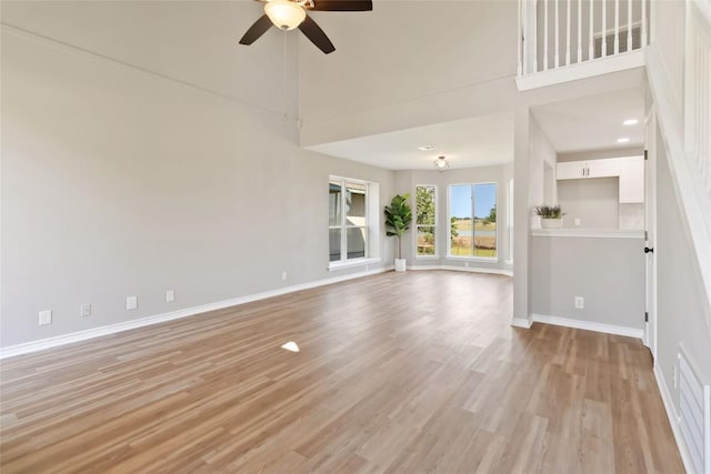 1145 Lago Vista St, San Marcos, TX 78666 - unfurnished living room with ceiling fan, light wood-type flooring, baseboards, and a high ceiling