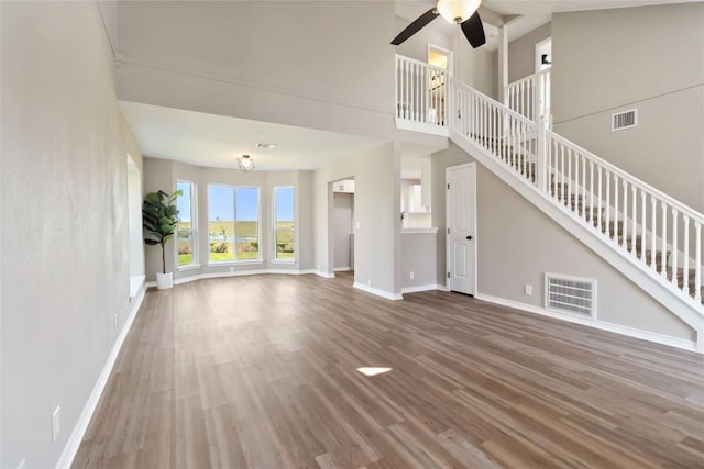 1145 Lago Vista St, San Marcos, TX 78666 - unfurnished living room featuring wood finished floors, stairs, baseboards, and a high ceiling