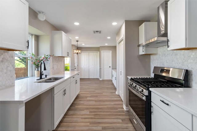 1145 Lago Vista St, San Marcos, TX 78666 - kitchen with gas stove, a sink, wall chimney exhaust hood, light wood finished floors, and tasteful backsplash