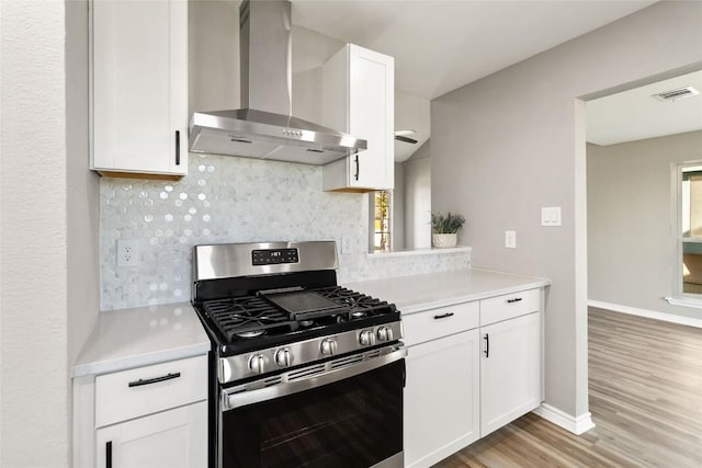 1145 Lago Vista St, San Marcos, TX 78666 - kitchen featuring wall chimney range hood, stainless steel range with gas stovetop, decorative backsplash, light wood-type flooring, and light countertops