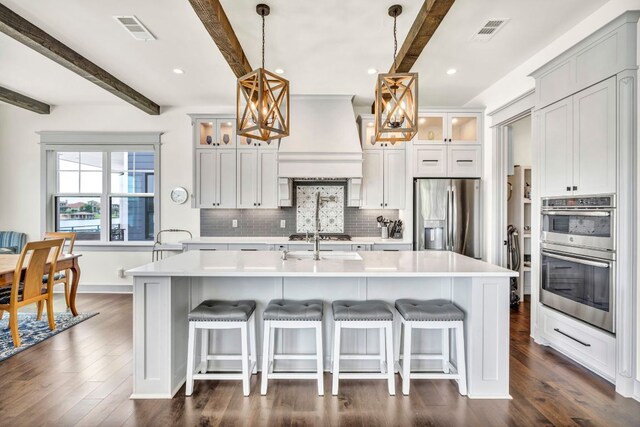 127 Cypress Shores Ln, Kingsland, TX 78639 - kitchen featuring appliances with stainless steel finishes, beam ceiling, decorative backsplash, light countertops, and glass insert cabinets