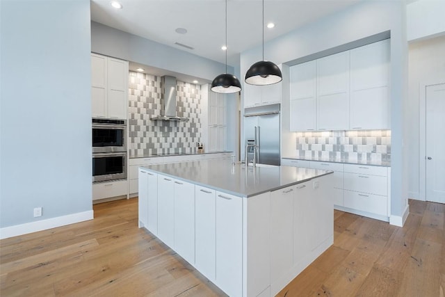 7816 Lynchburg Dr, Austin, TX 78738 - kitchen featuring wall chimney exhaust hood, appliances with stainless steel finishes, backsplash, light wood finished floors, and recessed lighting