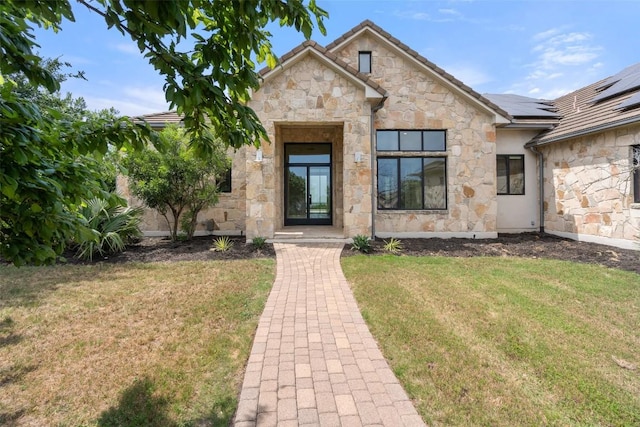 7816 Lynchburg Dr, Austin, TX 78738 - view of exterior entry featuring stone siding, a lawn, and solar panels
