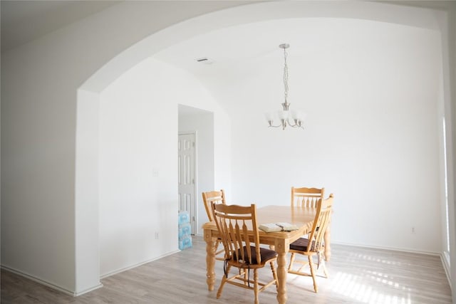 9305 Pioneer Forest Dr, Austin, TX 78744 - dining area featuring arched walkways, a chandelier, light wood finished floors, baseboards, and lofted ceiling