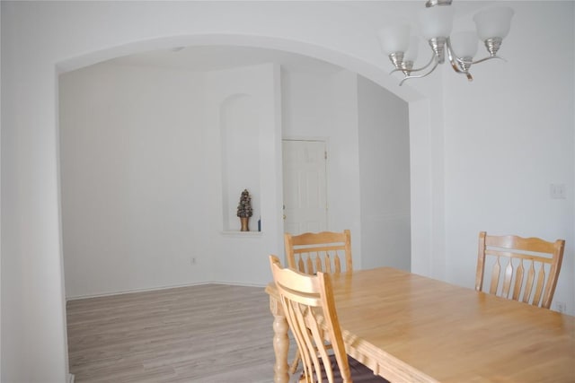 9305 Pioneer Forest Dr, Austin, TX 78744 - dining area featuring arched walkways, a chandelier, and light wood-style flooring