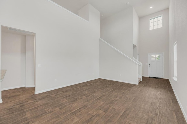 2900 Tweedy Trl, Pflugerville, TX 78660 - unfurnished living room featuring dark wood-type flooring, a high ceiling, stairway, and recessed lighting