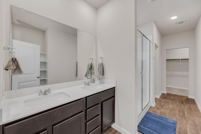 2900 Tweedy Trl, Pflugerville, TX 78660 - bathroom featuring a shower stall, a walk in closet, wood finished floors, and double vanity