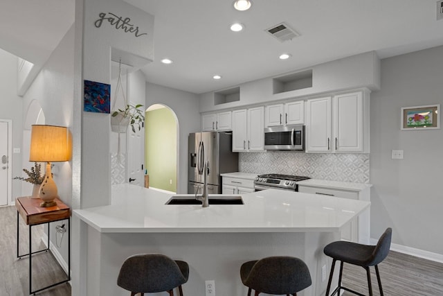 2208 Barnett Dr, Cedar Park, TX 78613 - kitchen featuring appliances with stainless steel finishes, light wood-style flooring, tasteful backsplash, a kitchen breakfast bar, and recessed lighting