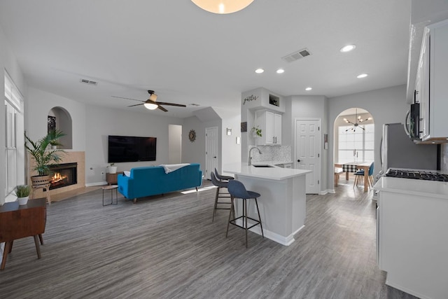 2208 Barnett Dr, Cedar Park, TX 78613 - kitchen featuring wood finished floors, baseboards, a kitchen breakfast bar, a tiled fireplace, and light countertops