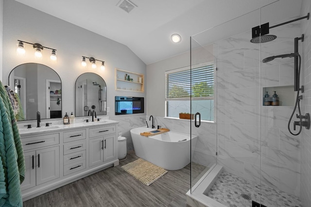 2208 Barnett Dr, Cedar Park, TX 78613 - bathroom with lofted ceiling, a shower stall, a freestanding bath, double vanity, and wood finished floors
