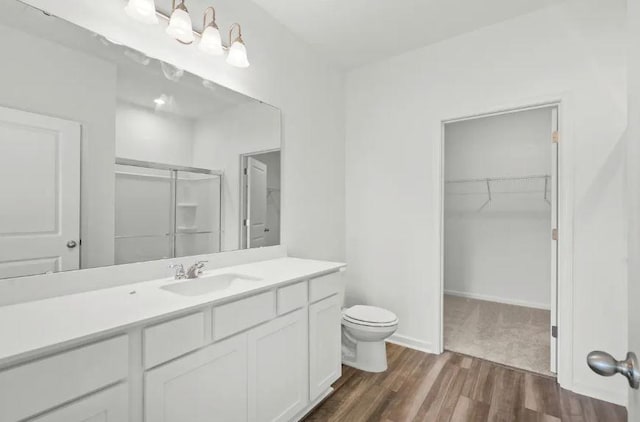 129 Bridgeview Dr, Hutto, TX 78634 - bathroom with an enclosed shower, wood finished floors, toilet, vanity, and a spacious closet