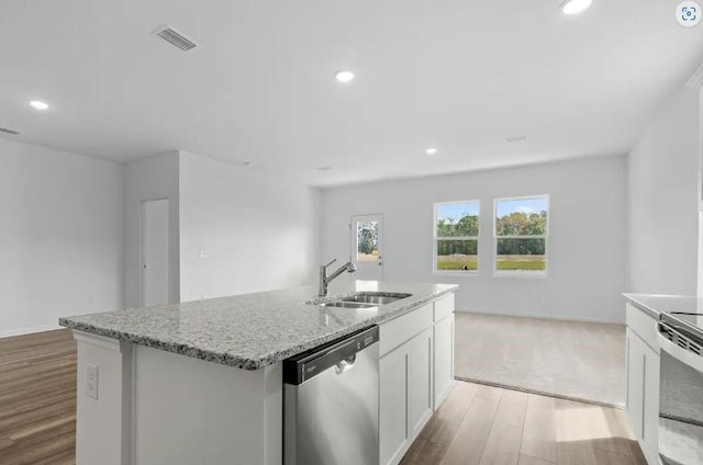 129 Bridgeview Dr, Hutto, TX 78634 - kitchen featuring a sink, appliances with stainless steel finishes, light wood-type flooring, an island with sink, and light stone counters