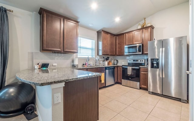 1678 Woodlands Dr, Kyle, TX 78640 - kitchen featuring appliances with stainless steel finishes, a peninsula, backsplash, lofted ceiling, and light tile patterned floors
