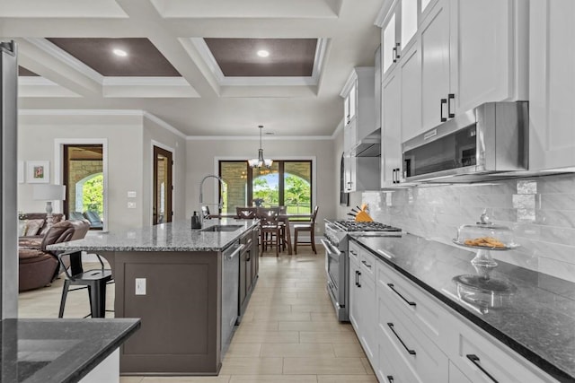 kitchen featuring appliances with stainless steel finishes, a sink, a kitchen breakfast bar, decorative backsplash, and dark stone countertops