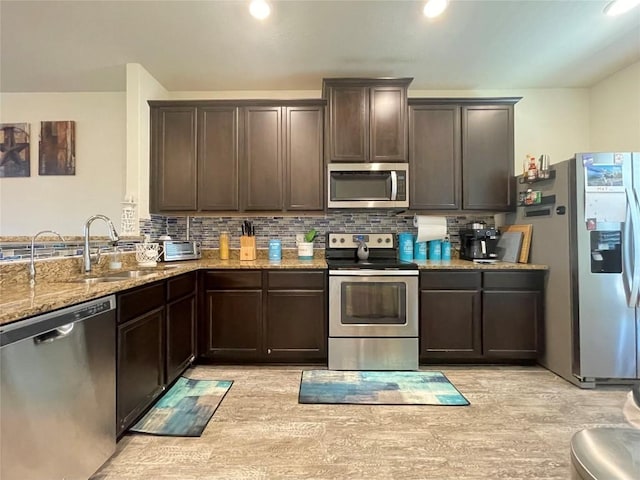 19900 Hubert R Humphrey Rd, Manor, TX 78653 - kitchen featuring appliances with stainless steel finishes, a sink, dark brown cabinetry, light stone countertops, and decorative backsplash