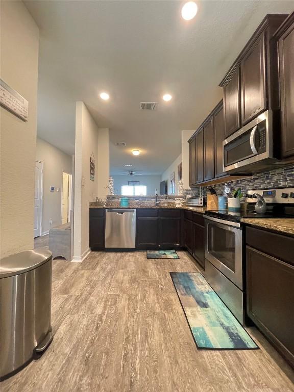 19900 Hubert R Humphrey Rd, Manor, TX 78653 - kitchen featuring stainless steel appliances, dark brown cabinetry, light wood-style flooring, backsplash, and recessed lighting