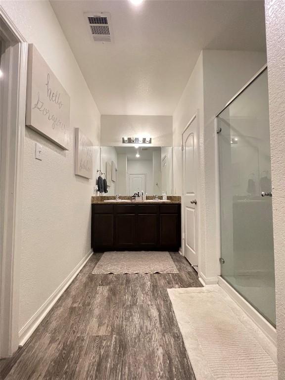 19900 Hubert R Humphrey Rd, Manor, TX 78653 - bathroom featuring wood finished floors, a stall shower, and double vanity