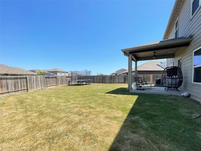 19900 Hubert R Humphrey Rd, Manor, TX 78653 - fenced backyard with a trampoline, a ceiling fan, and a patio