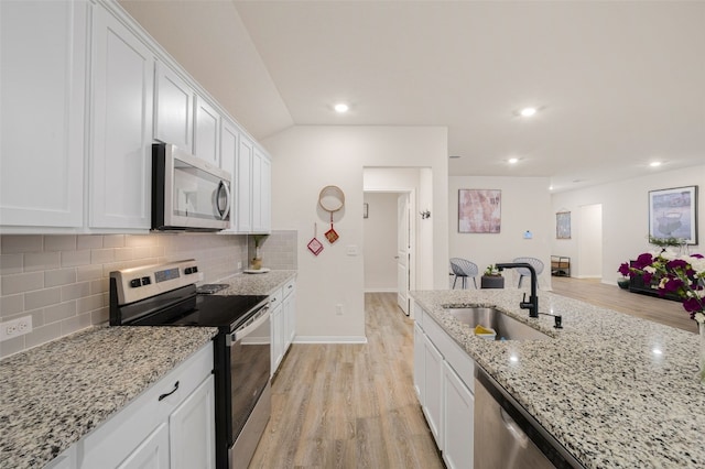 109 Egret Dr, Bastrop, TX 78602 - kitchen with appliances with stainless steel finishes, a sink, light wood-style flooring, white cabinetry, and recessed lighting