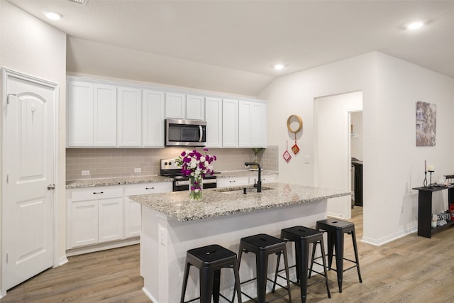 109 Egret Dr, Bastrop, TX 78602 - kitchen featuring stainless steel appliances, a sink, backsplash, light wood finished floors, and lofted ceiling