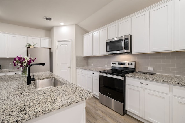 109 Egret Dr, Bastrop, TX 78602 - kitchen featuring appliances with stainless steel finishes, a sink, light wood-style floors, white cabinetry, and lofted ceiling