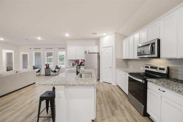 109 Egret Dr, Bastrop, TX 78602 - kitchen with stainless steel appliances, a sink, tasteful backsplash, light wood-style floors, and open floor plan