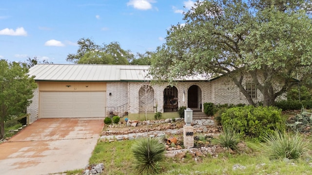 1603 Purple Sage, Horseshoe Bay, TX 78657 - view of front of property with brick siding, an attached garage, driveway, metal roof, and a standing seam roof