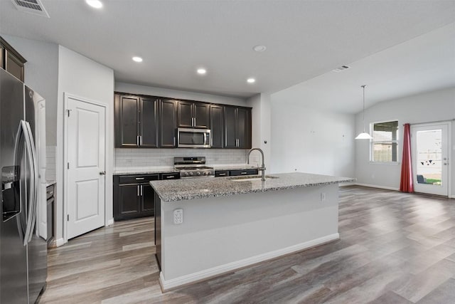16816 Caperi Dr, Pflugerville, TX 78660 - kitchen featuring appliances with stainless steel finishes, a sink, light wood finished floors, tasteful backsplash, and light stone counters