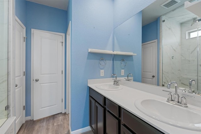 16816 Caperi Dr, Pflugerville, TX 78660 - bathroom featuring a marble finish shower, double vanity, wood finished floors, and baseboards