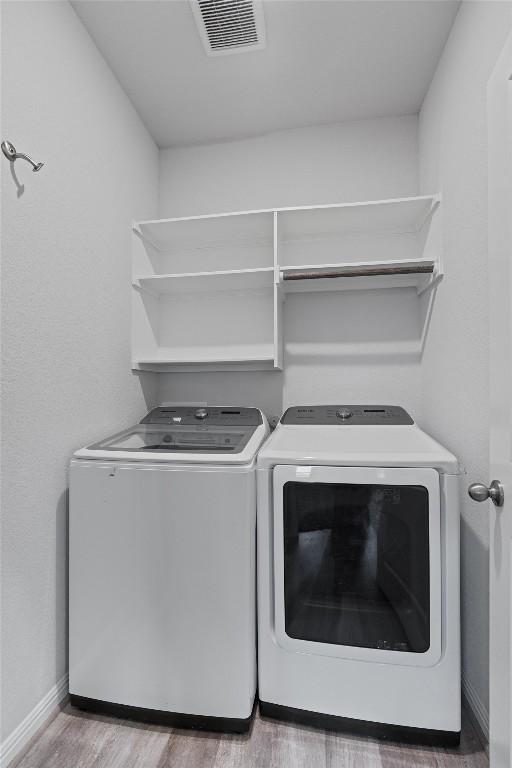 16816 Caperi Dr, Pflugerville, TX 78660 - laundry area featuring washing machine and dryer, wood finished floors, and baseboards
