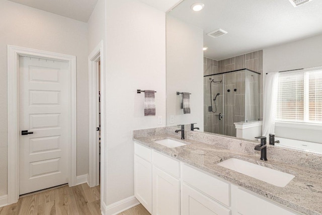 119 Nandina Path, Bastrop, TX 78602 - bathroom with a stall shower, double vanity, wood finished floors, and baseboards