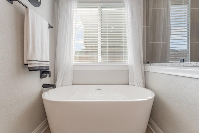 119 Nandina Path, Bastrop, TX 78602 - bathroom with a freestanding tub, healthy amount of natural light, and a textured wall