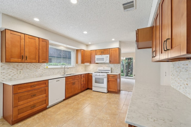 13204 Tamayo Dr, Austin, TX 78729 - kitchen featuring white appliances, a sink, brown cabinets, decorative backsplash, and a textured ceiling