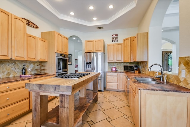 4908 Canyon Ranch Trl, Spicewood, TX 78669 - kitchen featuring stainless steel appliances, light brown cabinetry, a sink, arched walkways, and tasteful backsplash