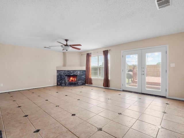 2727 High Point Dr, Round Rock, TX 78664 - unfurnished living room featuring french doors, a textured ceiling, ceiling fan, baseboards, and a premium fireplace